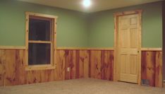 an empty room with green walls and wood paneling