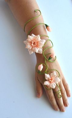 a woman's hand with flowers on it and green string attached to the wrist