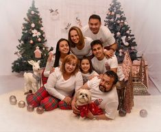 a group of people posing for a photo in front of a christmas tree with their dog