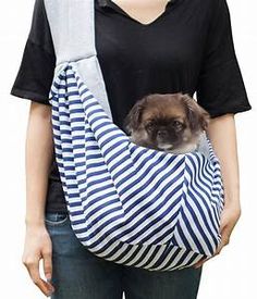 a woman holding a small dog in a sling on her back while wearing a black and white striped shirt