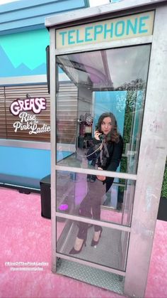 a woman is standing in a phone booth