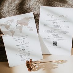 two wedding cards sitting on top of each other next to a flower and a piece of paper