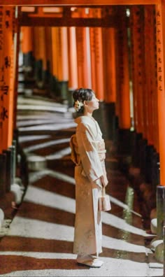 a woman standing in front of an orange building with columns on each side and the word,