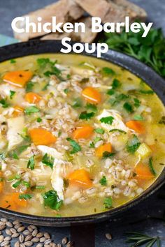 chicken barley soup in a cast iron skillet with carrots and parsley on the side