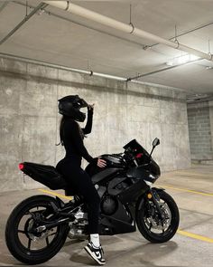 a woman in black is sitting on a motorcycle