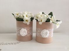 two vases with white flowers and lace on them