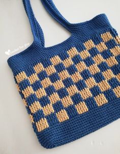 a crocheted blue and tan purse sitting on top of a white countertop