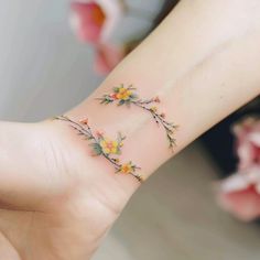 a woman's wrist tattoo with yellow flowers on the inside of her left hand