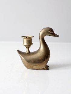 a brass duck shaped candle holder on a white surface