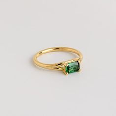 a gold ring with an emerald colored stone