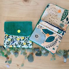 two small wallets sitting next to each other on top of a wooden table with pebbles