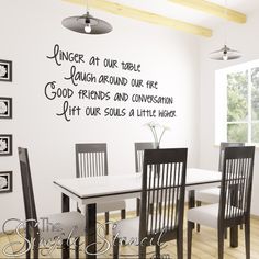 a dining room table with four chairs and a wall decal that says, anger at our table laugh around our fire good friends and conversation hit our