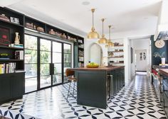 a kitchen with black and white tile flooring and gold pendant lights hanging from the ceiling