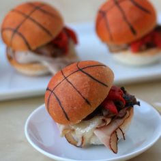 two small sandwiches with meat and cheese on them are sitting on plates next to utensils