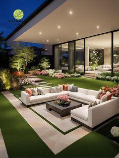 a living room filled with lots of furniture next to a lush green field at night