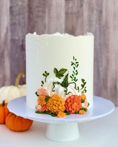 a white cake with orange and yellow flowers on it sitting on top of a table