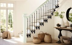 a staircase with black iron railings and pots on the floor in front of it