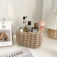 a rope basket with various items in it sitting on a table next to a magazine