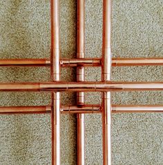 four copper pipes are connected to each other on the carpeted floor in this photo