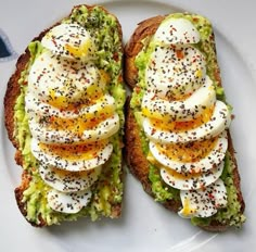 two pieces of bread with eggs and other toppings on it sitting on a plate