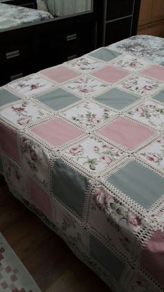 a bed with a pink and grey quilt on it