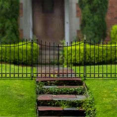 a set of steps leading up to a gated in area with grass and bushes