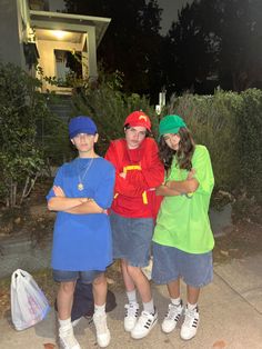 three young people dressed in costumes standing next to each other on a sidewalk at night