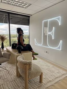 a woman sitting on top of a wooden table in front of a neon sign that reads j f