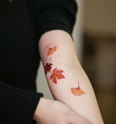 a woman's arm with two leaves on it and one falling off the arm