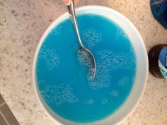 a person holding a spoon in a bowl filled with blue liquid