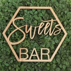 a wooden sign that says candy bar on top of a green bush with the words candy bar written in cursive font