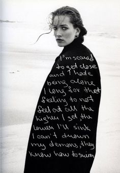 a woman standing on top of a beach covered in a black blanket with writing on it