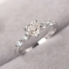 a diamond ring with three stones on it's side, sitting on a white cloth