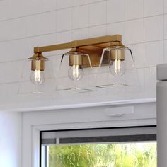 a bathroom light with three lights on the wall above it and a window in the background