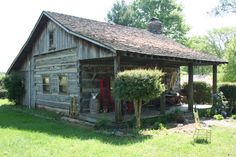 an old log cabin with plants growing out of it's roof and the front door open