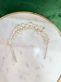 a white and gold headband with pearls on it sitting on a marble platter