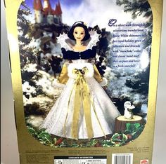 the doll is wearing a white dress with gold trimmings and a black top