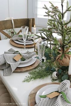 a dining room table set for christmas with place settings and greenery on the plates