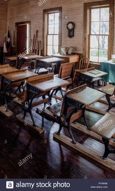 an old school room with wooden desks and chairs in the center, looking out onto the