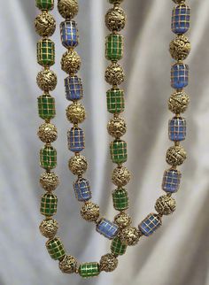 Enhance your collection with these two Caged Bead Necklaces. One features green beads, and the other showcases blue beads. Both necklaces are complemented by gold foil nakshi balls. The unique caged design adds texture and elegance, making it a versatile piece for both casual and formal occasions. Perfect for those who appreciate detailed craftsmanship and a touch of color in their jewelry collection. Material : 24Kt Gold foil, Lac Stones: Semi precious blue beads, semi precious green beads, gol Nakshi Balls, Bead Necklaces, Gemstone Beaded Necklace, Green Beads, Tourmaline Necklace, Pin Pendant, 24kt Gold, Green Necklace, Pendant Rings