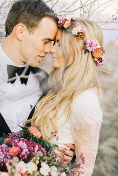 a man and woman standing next to each other with flowers in their hair