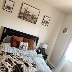 a bed with two pictures on the wall above it and a pillow in front of it