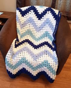 a crocheted blanket sitting on top of a brown chair