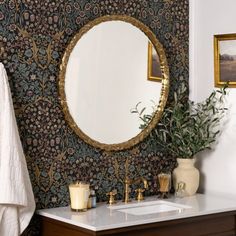 a bathroom with a sink and mirror next to a wallpapered wall behind it