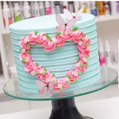 there is a cake decorated with flowers and butterflies on the top of it, in the shape of a heart