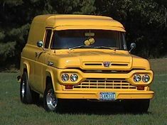 an old yellow truck is parked in the grass