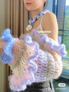 the woman is wearing a crocheted sweater with ruffles on her arms