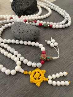 Beautiful Howlite Mala from Nepal and Mountain shell beads Mala necklace. You can choose between the mala that is made with howlite beads (white with gray) and mix metal beads from Nepal, or the all white mala necklace, which is made with mountain shell beads and a yellow mantra symbol. A unique praying mala that can be used as a necklace or as an ornament. The mala has no clasp, you wear it over the head. --The Mala with the metal beads and the red beads has a total length of 48.2cm- 19 inch lo Symbolic White Round Bead Jewelry, Symbolic White Jewelry With Round Beads, White Beaded Bracelets With 108 Beads For Meditation, White Adjustable Mala With Gemstone Beads, Adjustable White Mala With Gemstone Beads, Adjustable White Gemstone Beads Mala, White 108 Beads Jewelry As A Gift, Symbolic White Beaded Jewelry, Adjustable White Mala With 8mm Beads