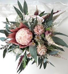 an arrangement of flowers and greenery on a white background