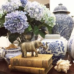 an elephant figurine sitting on top of books next to vases and flowers